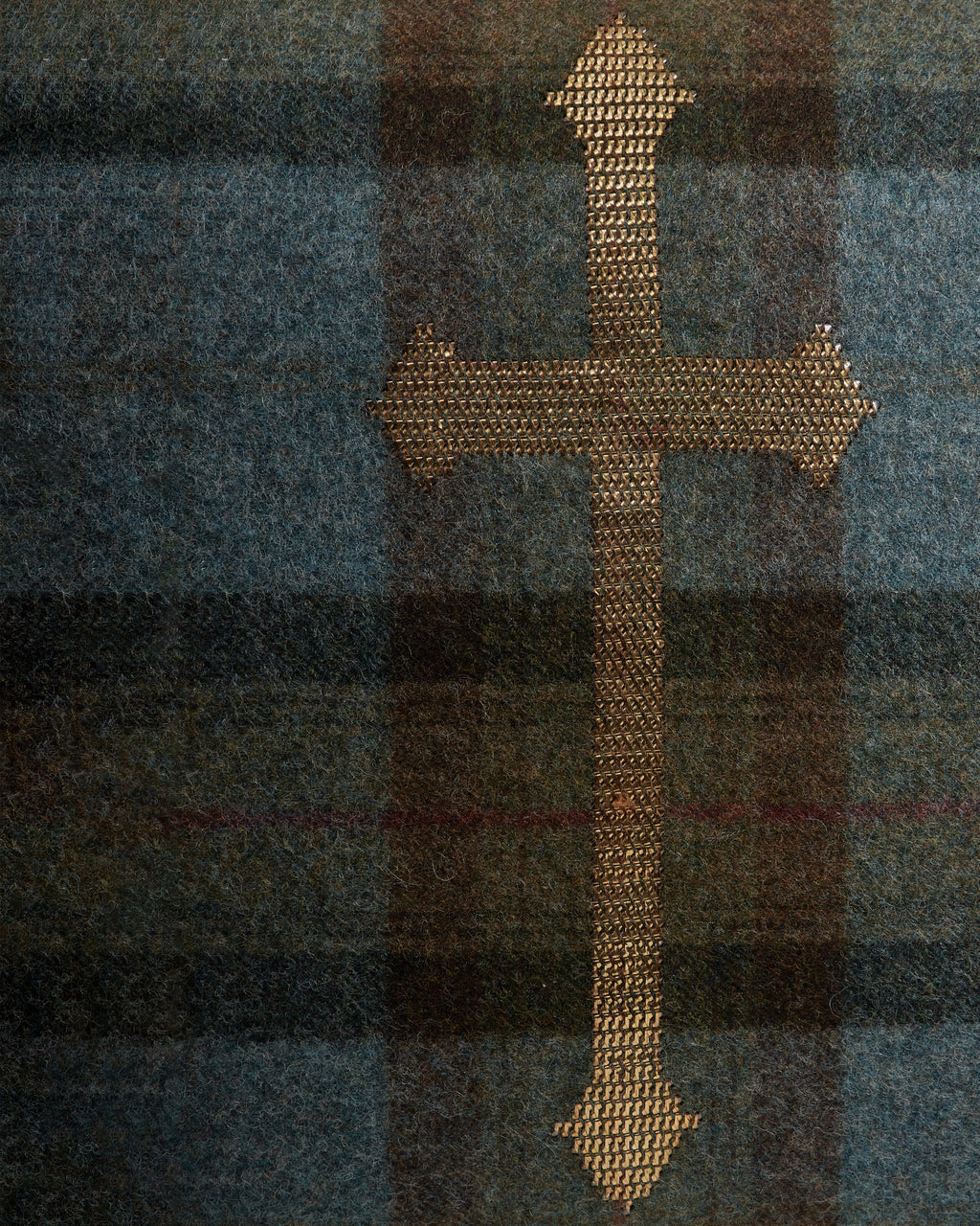 Gold cross on a plaid fabric background