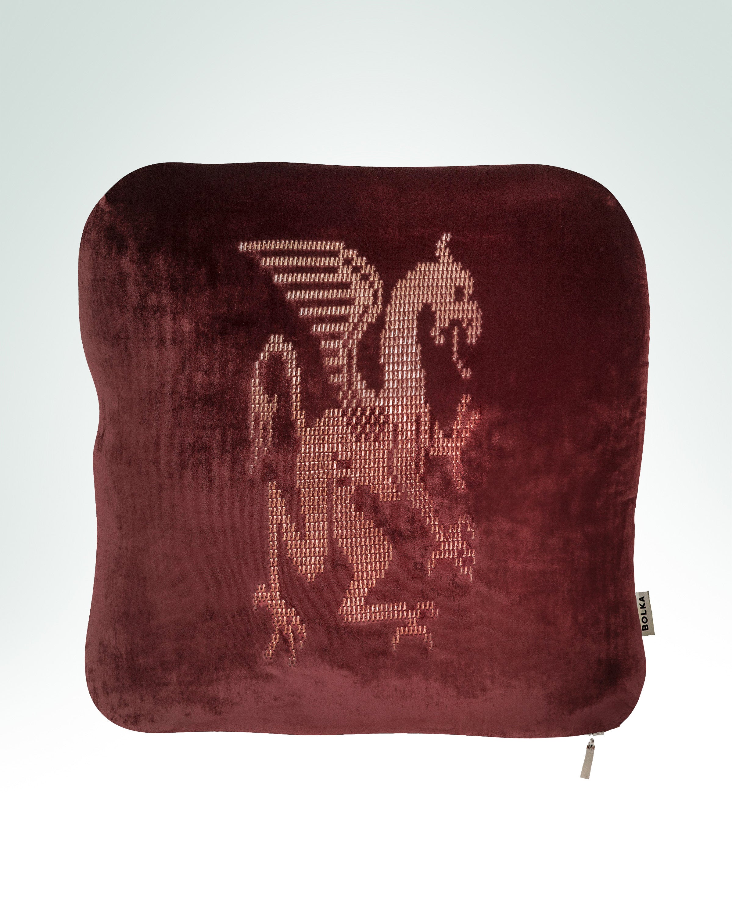 griffin hand-embroidered on oxblood velvet cushion in gold thread.