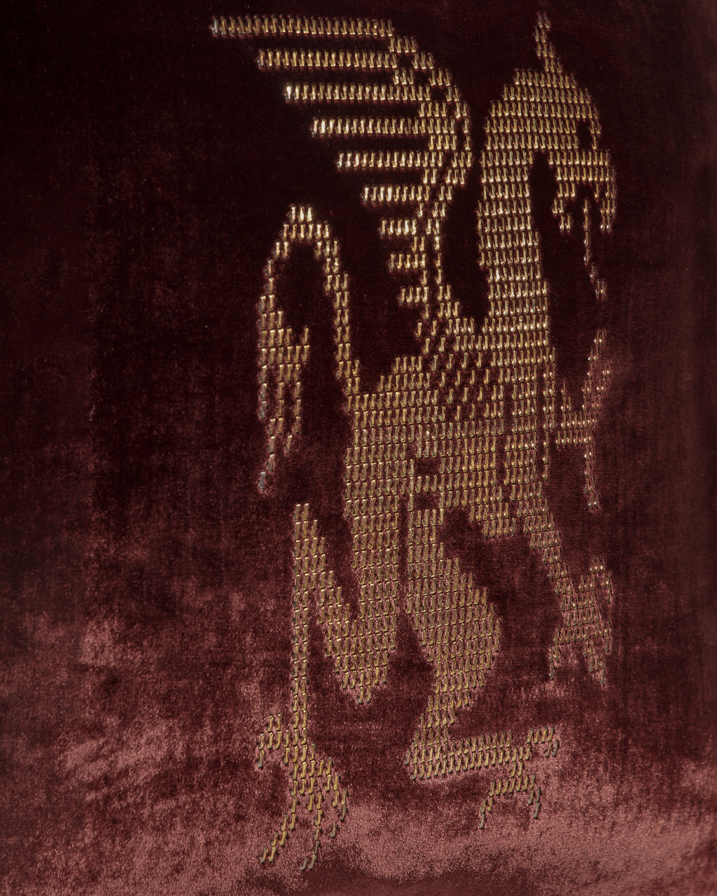 griffin hand-embroidered on oxblood velvet cushion in gold thread.