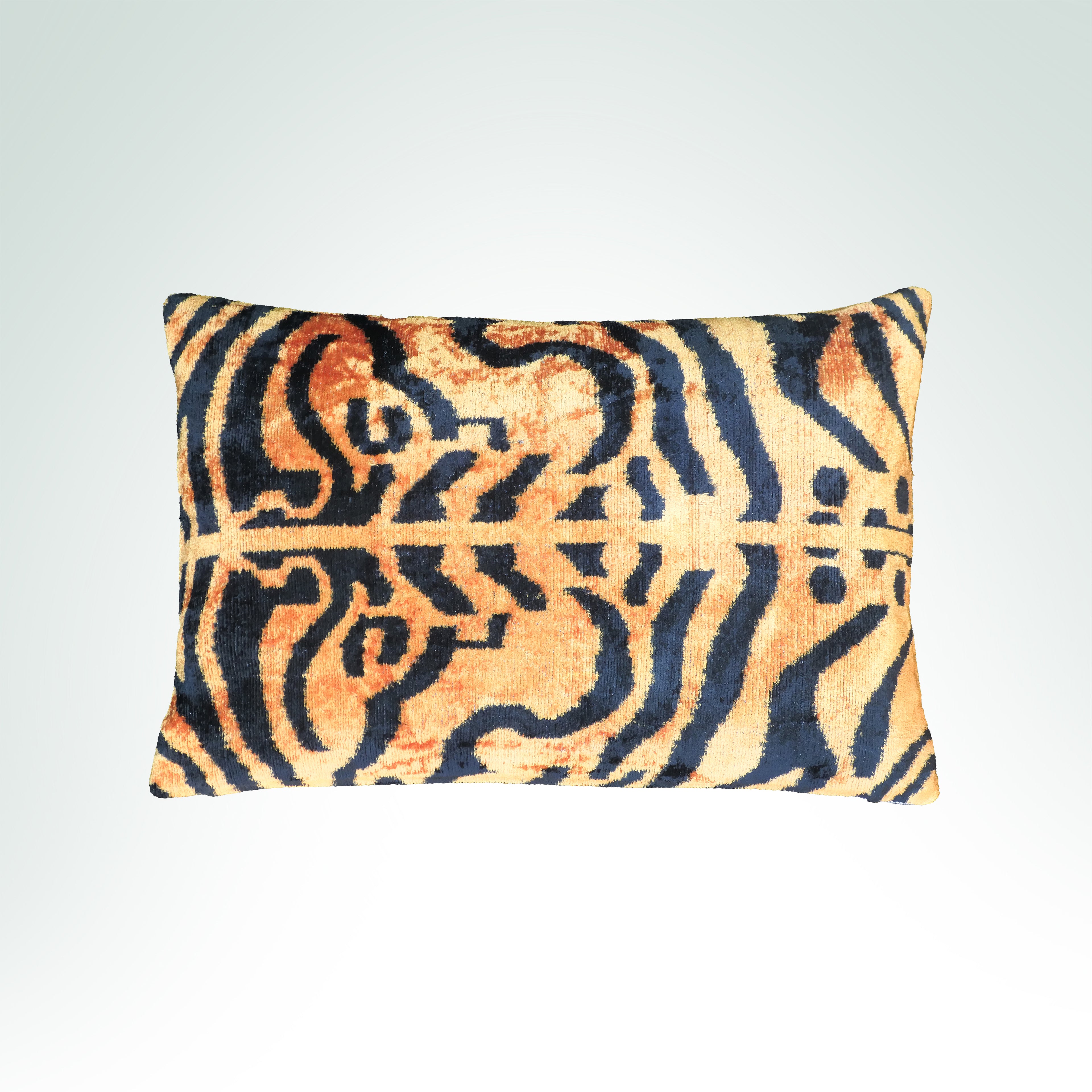 A bold tiger-stripe pattern in black and warm orange-brown on a light beige velvet ikat cushion.